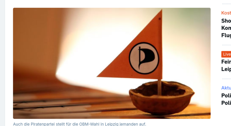 Eine Walnussschale, in die ein orangefarbenes Piratenfähnchen gesteckt wurde, sodass sie wie ein kleines Segelboot aussieht.